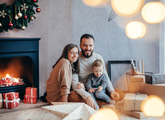 In a cozy Christmas scene, a young family gathers by the fireplace, surrounded by twinkling lights...