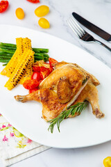 chicken thighs with corn, cherry tomatoes and herbs side view