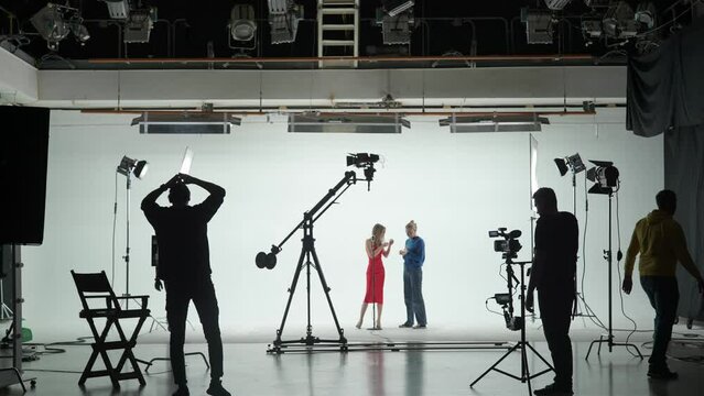 Professional filming pavilion with a white cyclorama. The process of preparing for the shooting of a music video. Director, Cameraman and crew in Backstage.