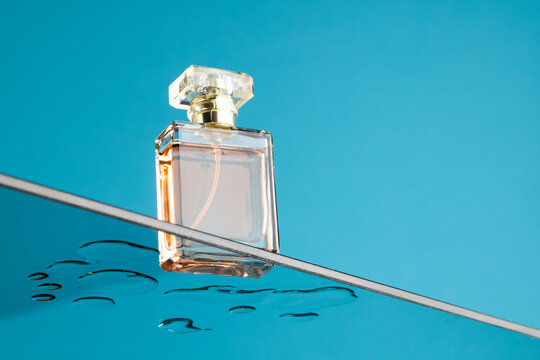 Beauty product perfume bottle on glass shelf, copy space on blue background