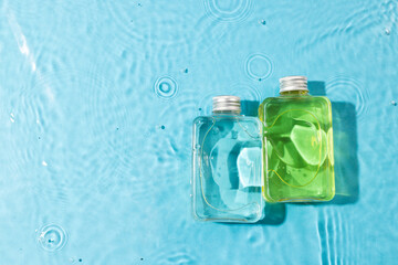 Beauty product bottles in water with copy space background on blue background