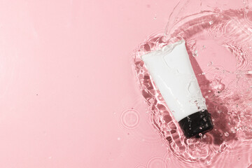 Beauty product tube in water with copy space background on pink background