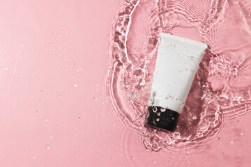 Beauty product tube in water with copy space background on pink background
