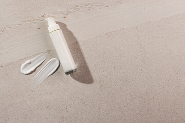 Beauty product bottle with pump and cream smudges with copy space on stone background