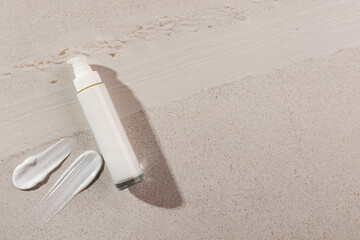 Beauty product bottle with pump and cream smudges with copy space on stone background