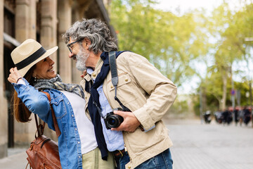 Lovely senior couple of tourist enjoying vacation together in city street. Older mature people in love having fun sightseeing european city during vacation or weekend getaway. Copy space for text - obrazy, fototapety, plakaty