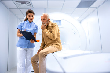 MRI technician preparing patient for scanning procedure in hospital examination room.