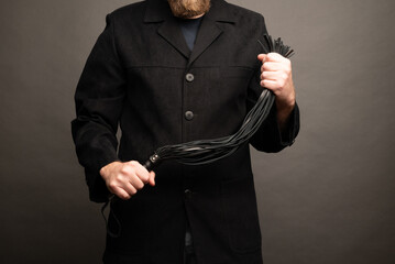 male dominant holds a leather whip Flogger for hard BDSM sex with spanking