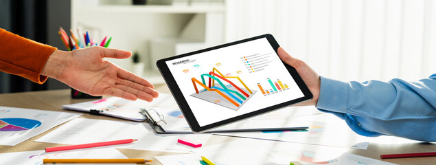 Fototapeta na wymiar Startup company employee working together using tablet analyzing BI dashboard paper on financial data report and planning strategic marketing for business success in panorama banner. Synergic