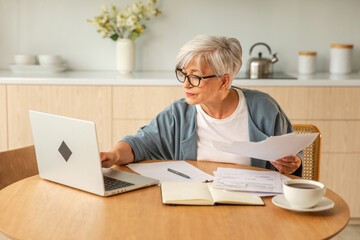 Middle aged senior woman sit with laptop and paper document, Pensive older mature lady reading...