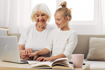 Laptop bonding hugging child selfie granddaughter smiling family education sofa togetherness grandmother
