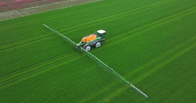 Creil, The Netherlands, 15th of April, 2023. Aerial drone view on a tractor spraying the land. Agricultural famer working the land.