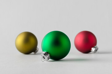 Green, yelow and red Christmas balls on a seamless grey background.