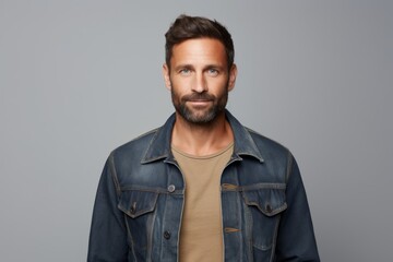 Fototapeta premium Portrait of a glad man in his 30s sporting a rugged denim jacket against a white background. AI Generation