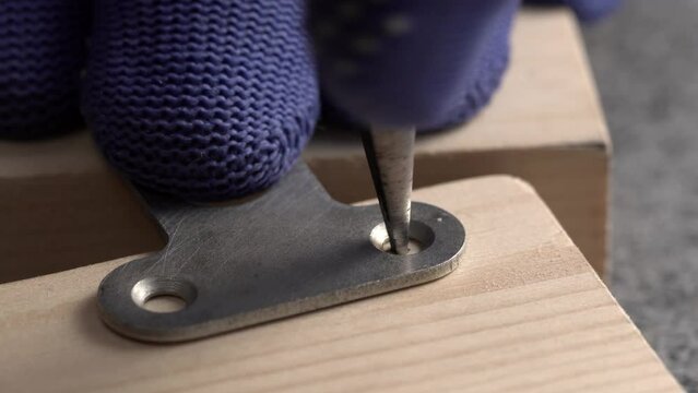 Carpenter marks a future hole in the board for a self-tapping screw to attach a furniture keyhole hanger, close-up