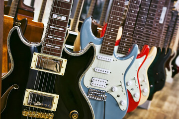 A collection of electric solid body guitars hanging in a row