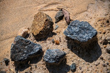 small black stone cubes on sand ground in close up