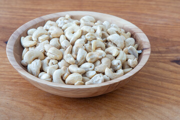 Cashews in a wooden bowl. Nuts are healthy food. Wooden background. Cashew kernel