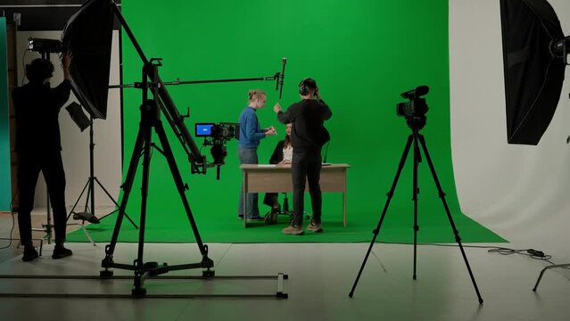 News anchor at work, process of preparing for news shooting, view of a backstage studio TV news shooting, chroma key template.