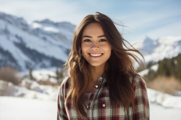 Portrait of a cheerful woman in her 20s dressed in a relaxed flannel shirt against a snowy mountain range. AI Generation