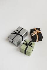 Stylish gift boxes: black, steel, olive. They lie on the white floor. Holidays, New Year, birthday.