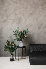 Winter green bouquets of pine needles and other plants on a gray background. Eco minimalism. Interior bouquet.