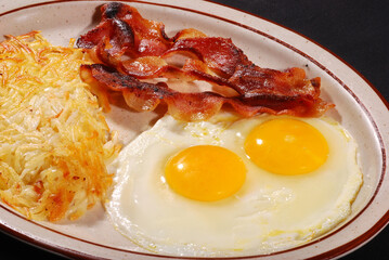 fried eggs and bacon with hash browns potato