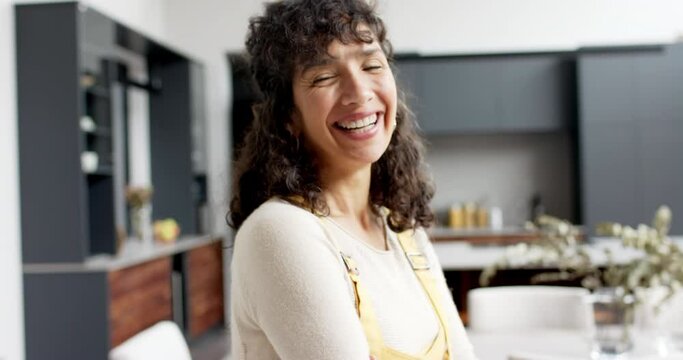 Portrait of happy mature caucasian woman with long curly hair smiling at home, slow motion