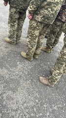 Shoes of Ukrainian military which are lined up on a gray asphalt surface