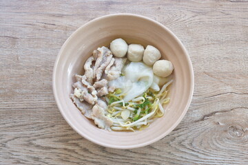 boiled white large noodles with soft slice pork and ball in clear soup on bowl