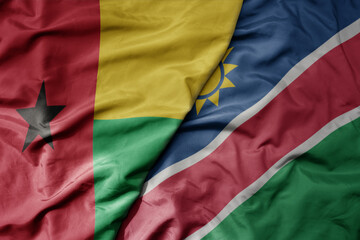 Fototapeta premium big waving national colorful flag of namibia and national flag of guinea bissau .