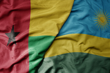 big waving national colorful flag of rwanda and national flag of guinea bissau .