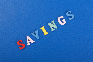 SAVINGS word on blue background composed from colorful abc alphabet block wooden letters, copy space for ad text. Learning english concept.