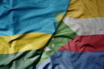 big waving national colorful flag of comoros and national flag of rwanda .