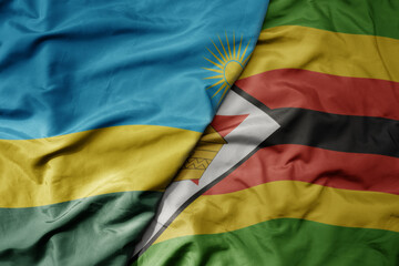 big waving national colorful flag of zimbabwe and national flag of rwanda .
