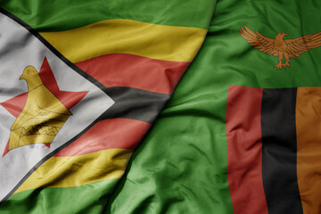 big waving national colorful flag of zambia and national flag of zimbabwe .