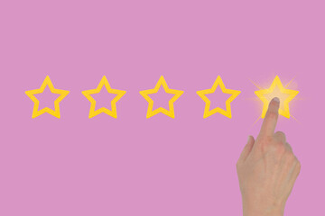Female hand leaves a rating of five stars out of five possible on a pink background. Concept of...