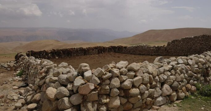 High-altitude stone corral for sheep. Stone fences, sheep pasture paddock located high in mountains. Empty sheep pen, high-altitude camp, corral, paddock for keeping cattle and cloven-hoofed animals