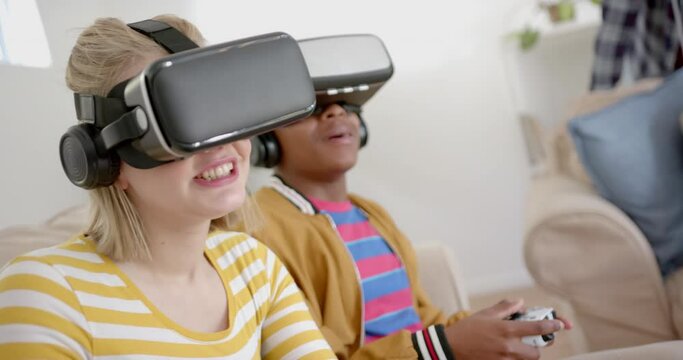 Happy diverse group of teenage friends with vr headsets playing video games at home, slow motion