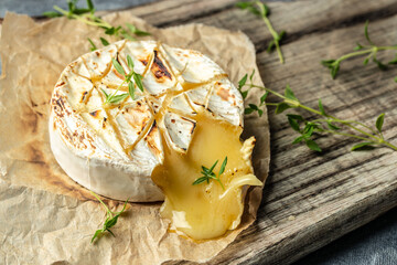 Traditional French homemade baked Camembert cheese with thyme on a wooden background. top view....