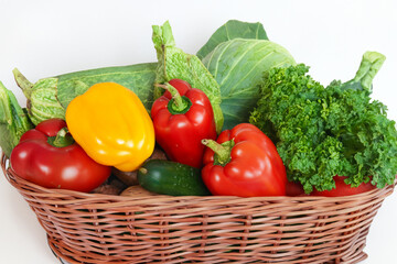 composition of vegetables. a set of fresh vegetables lie in a wicker basket on a white background, a large basket with vegetables