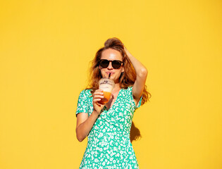 Woman drinking juice in front of yellow background. Summer lifestyle. 