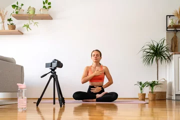 Fotobehang Yoga coach recording video of meditation exercise. Woman doing breathing exercise and meditation in lotus pose. © Barillo_Picture