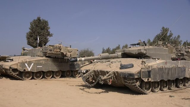 A handheld clip of two Israeli Merkava tanks, waiting for action on the desert soil. Be'eri, Israel.