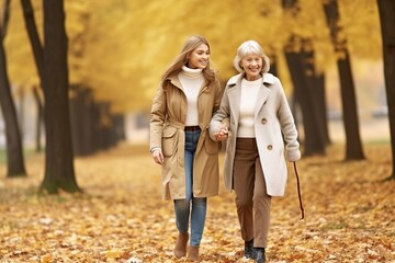 two woman  walking in the  autumn park, grandmother with grown-up granddaughter