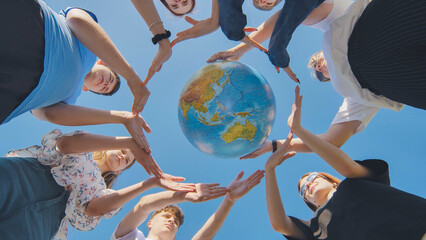 Young boys surround the globe of the world with their palms. The concept of preserving world peace.
