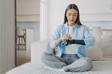 Obraz premium Serene young woman in meditation with a bionic arm, blending tranquility with technology in a modern setting