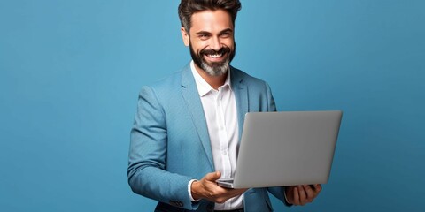 Donned in formal attire, a businessman exudes confidence while looking at a laptop with a joyous, friendly, and big smile, standing against a blue studio background