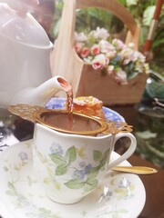 Pouring hot tea on cup with pot