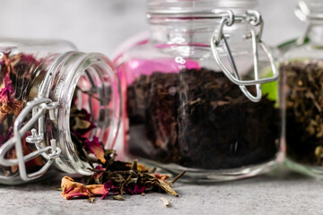 Zoom in shot of jar with dry scattered rose petels and defocused jars in the background.